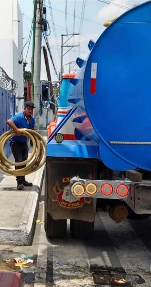 Camión cisterna y técnico con manguera listos para limpiar una fosa séptica